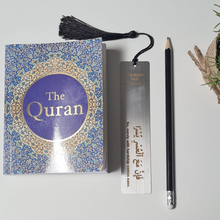 Load image into Gallery viewer, Personalised engraved metal bookmark with Islamic quote from the Quran next to an English translation of the Quran and a black pencil.